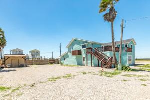 a house on the beach with a palm tree at Beach & Bay Views - Unit 2 - Bluewater Beach House in Surfside Beach