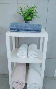 Un estante blanco con toallas y una planta. en Guest House VeryMary Eilat Stydio en Eilat