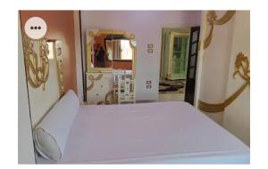 a white bed in a room with a mirror at Amira Hospitality House in Aswan