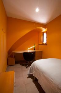 a bedroom with a bed and a desk and a chair at Masia Olivera in Sant Pau dʼOrdal