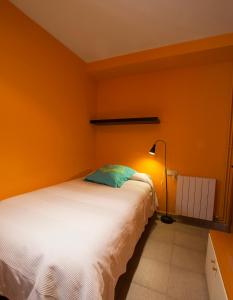 a bedroom with a bed with an orange wall at Masia Olivera in Sant Pau dʼOrdal