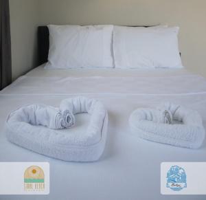 un letto bianco con due asciugamani arrotolati di Belize suit otel a Muğla