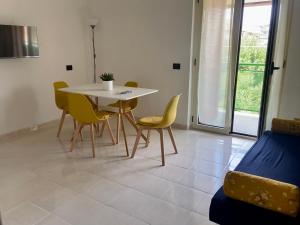 uma sala de jantar com uma mesa branca e cadeiras amarelas em Mimama em Telese Terme