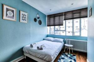 una camera da letto con pareti blu e un letto con uno sgabello di Appartement Love près des Grands Magasins - 6P a Parigi
