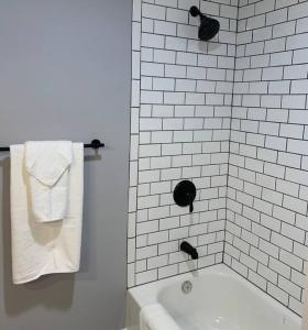a white bathroom with a tub and a white tile wall at Private Suite in Davison in Davison