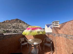 einen Tisch und Stühle auf einem Balkon mit Sonnenschirm in der Unterkunft Apartamentos Turisticos Juanita "Ope" in Archena