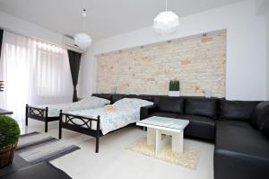 sala de estar con sofá negro y pared de ladrillo en Aries Apartments, en Bitola
