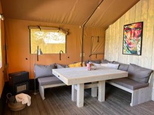 a table and benches in a tent at Safari Lodge Grou, luxe kamperen op een eiland! in Grou