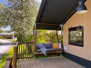 a porch with a couch on a deck at Safari Lodge Grou, luxe kamperen op een eiland! in Grou