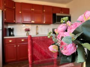 a kitchen with red cabinets and pink flowers on a table at Evansville Holiday House in Evansville