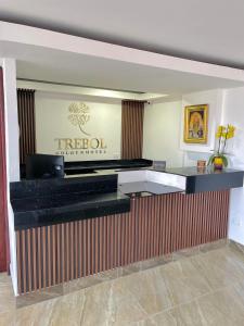 um balcão de recepção do hotel com uma placa na parede em TRÉBOL GOLDEN HOTEL em Ipiales