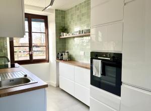 eine weiße Küche mit einer Spüle und einem Herd in der Unterkunft Appartement en plein centre ville in Milly-la-Forêt