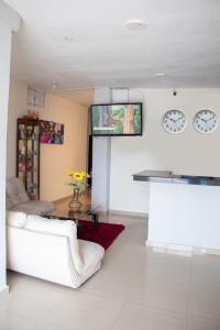 a living room with a white couch and a tv on the wall at RUTA DEL MAR INN HOTEL in Santa Marta