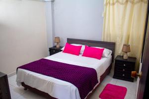a bedroom with a large bed with pink pillows at RUTA DEL MAR INN HOTEL in Santa Marta