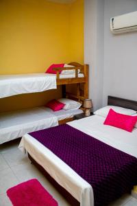 three beds in a room with red pillows at RUTA DEL MAR INN HOTEL in Santa Marta