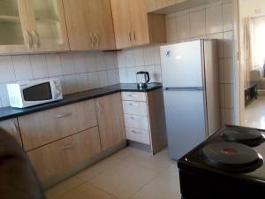 een keuken met een witte koelkast en een magnetron bij Kulu Lodge Apartments in Lusaka