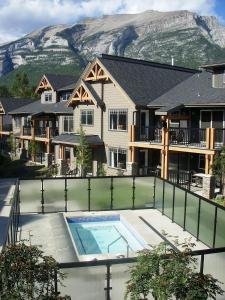 a house with a swimming pool in front of a mountain at Rocky Mountain Getaway in Canmore