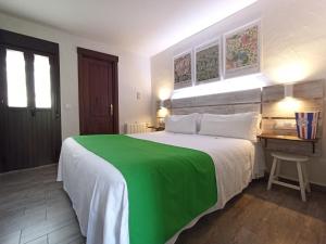 a bedroom with a green and white bed and a desk at LA JARANA Casa Hotel in Zahara de la Sierra