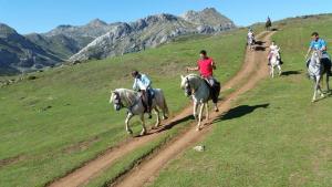 a group of people riding horses on a dirt road at Apartamentos Andrea in Belmonte de Miranda