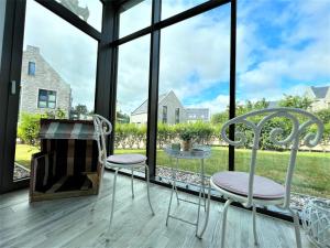 deux chaises et une table sur une véranda grillagée avec fenêtres dans l'établissement Haus Undine, Deichhörn 6a, à Dangast