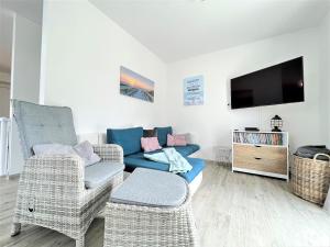 un salon avec un canapé, des chaises et une télévision dans l'établissement Haus Undine, Deichhörn 6a, à Dangast
