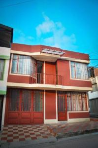 a red house with red doors and a balcony at Casa amplia con garaje in Fusagasuga