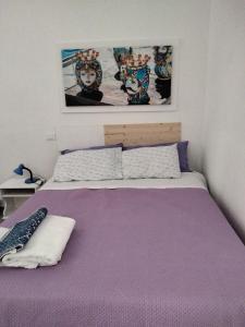 Schlafzimmer mit einem Bett mit lila Bettwäsche und Gemälden in der Unterkunft Casetta Blu Mondello zona Partanna in Palermo