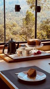 una mesa con una bandeja con un pastel en una mesa en Cabanas da Mata - Cabana Flamboyant - Casa Branca en Brumadinho