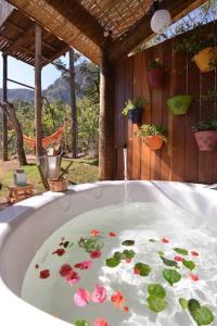 a bath tub with flowers in the water at Cabanas da Mata - Cabana Flamboyant - Casa Branca in Brumadinho