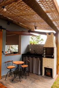 una cocina al aire libre con taburetes y un horno de ladrillo en Cabanas da Mata - Cabana Flamboyant - Casa Branca en Brumadinho