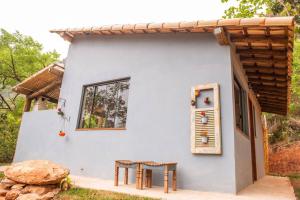 Casa blanca pequeña con mesa y ventana en Cabanas da Mata - Cabana Flamboyant - Casa Branca en Brumadinho