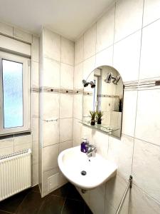La salle de bains blanche est pourvue d'un lavabo et d'un miroir. dans l'établissement Ferienwohnung Waldliebe, à Schierke