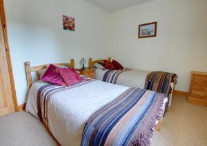 a bedroom with two beds and a dresser at Avocet Cottage in Dersingham