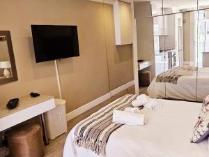Una habitación de hotel con dos camas y un televisor de pantalla plana. en Studio 37 Hyde Park Apartments, en Ciudad del Cabo