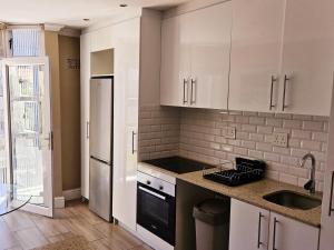 Una cocina con gabinetes blancos y un fregadero. en Studio 37 Hyde Park Apartments, en Ciudad del Cabo 15 fotos más