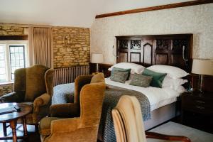 a bedroom with a large bed and two chairs at The Manor House Hotel and Golf Club in Castle Combe