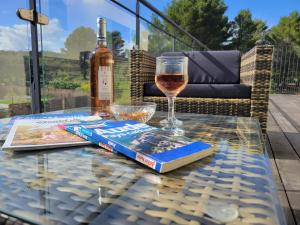een glazen tafel met een boek en een fles wijn bij Domaine d'Azéou in Laure-Minervois