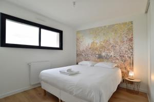 ein Schlafzimmer mit einem weißen Bett und einem Gemälde an der Wand in der Unterkunft Villa Armor Glaz - Maison avec jacuzzi in Saint-Cast-le-Guildo