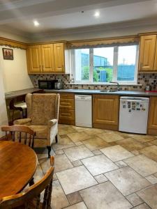 una cocina con armarios de madera, mesa y sillas en Marian Place House en Cahersiveen