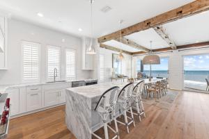 パナマ・シティ・ビーチにあるGulf Front Luxurious Home with Private Pool and Beach Access homeの白いキャビネットと椅子付きの大きな島のあるキッチンが備わります。