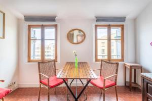 a dining room with a table and chairs and windows at Le Caisserie - Cosy studio Marseillais - Panier in Marseille