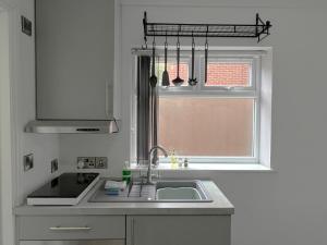 a white kitchen with a sink and a window at Melbury Rooms & Studios in Exeter