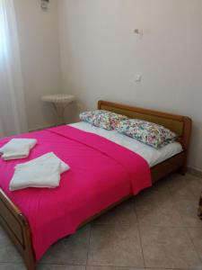 a bed with a pink blanket and pillows on it at Gold Crest House Vrasna in Nea Vrasna