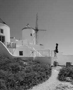 a person riding a skateboard on a rail next to a building at The Sunset Windmill in Oia
