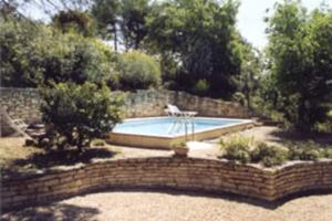 uma piscina num quintal com uma parede de tijolos em Detached holiday home with private pool in the village of Roussillon em Murs