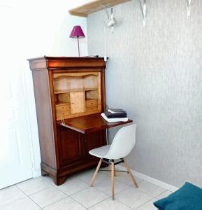 einen Holzschreibtisch mit einem Stuhl und einem Telefon in der Unterkunft Studio cosy avec jardin, La Jarrie, 23m², piscine partagée in La Jarrie + 18 Fotos