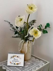 a vase with white flowers on a table with a card at Ferienwohnung am Pilsensee in Seefeld