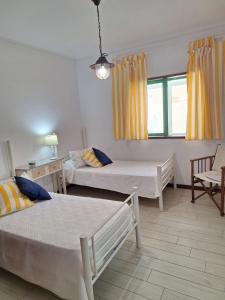 a bedroom with two beds and a window with yellow curtains at la casa de isa en aveiro in Aveiro