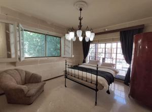 a bedroom with a bed and a chair and windows at Wilga Summit Apartment C in Qala