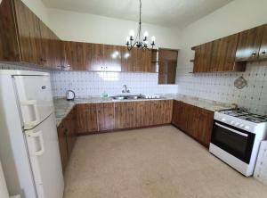 - une cuisine avec des placards en bois et un réfrigérateur blanc dans l'établissement Wilga Summit Apartment C, à Qala